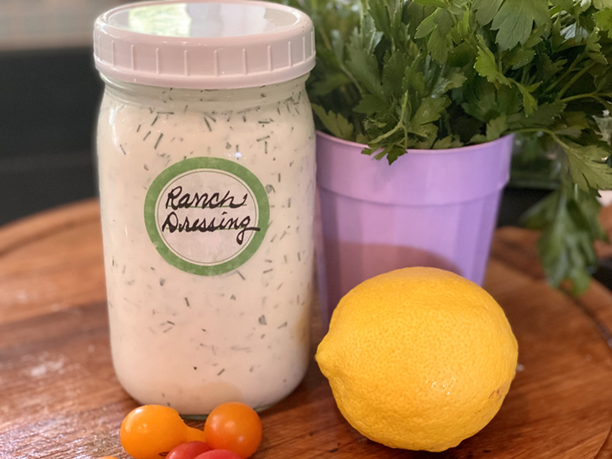Mason jar full of ranch dressing with fresh parsley and lemon in view.