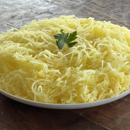Large bowl of spaghetti squash on a dark wood table.