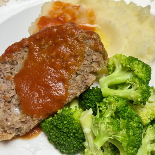 Mom's Easy Meatloaf with Tomato Sauce Topping plated with mashed potatoes and broccoli